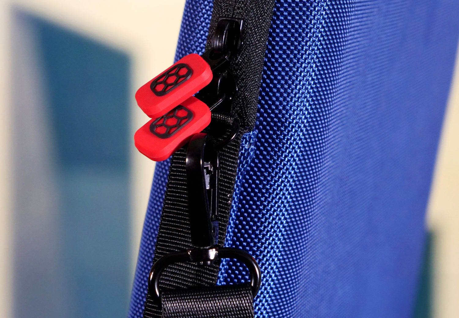 Close-up of Blue Comic Shell Graded Comic Travel case with red and black zipper pulls and shoulder strap hardware